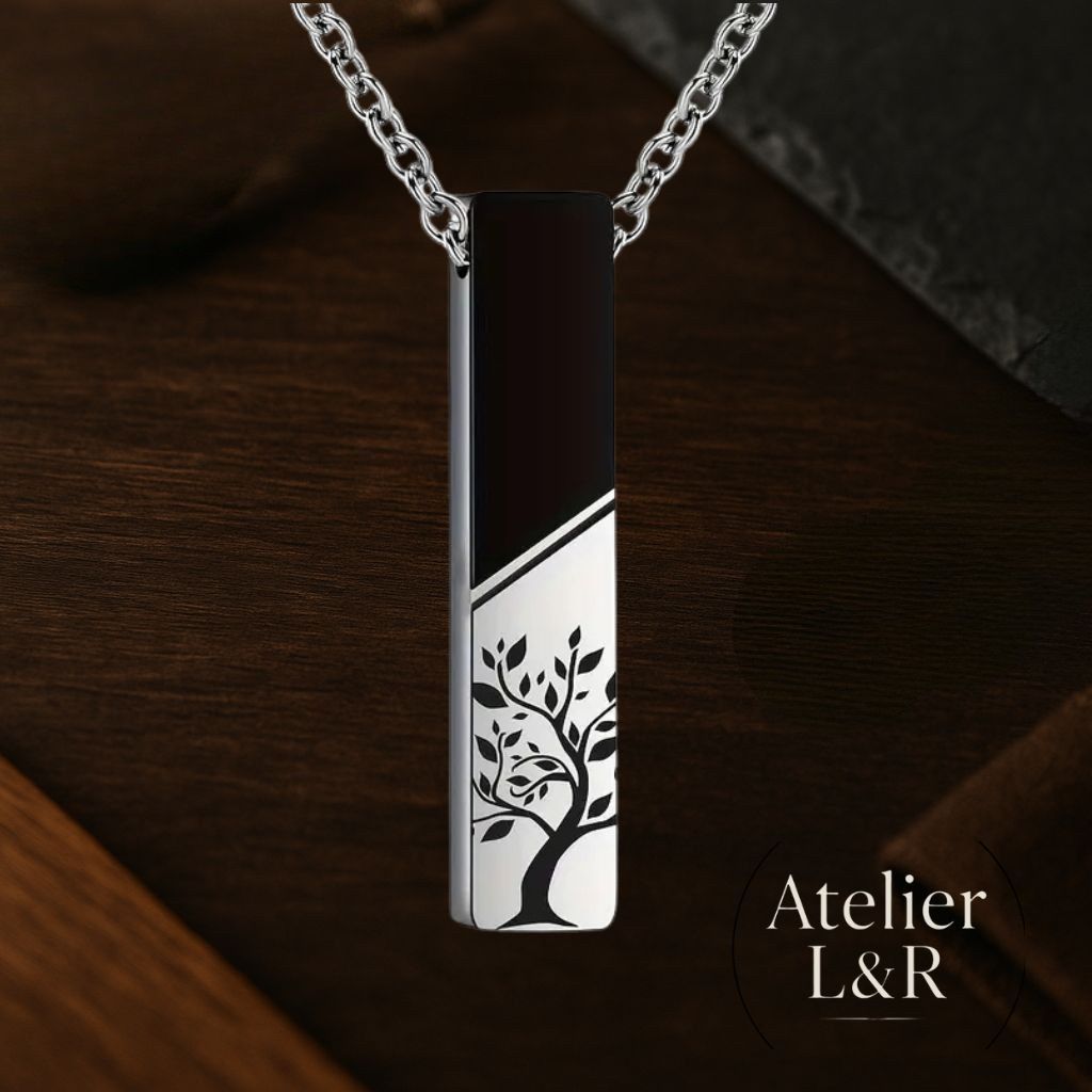 Pendentif en acier inoxydable gravé d’un arbre de vie, sur fond bois sombre, bijou signé Atelier L&R.